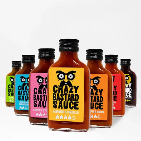 Verschiedene Crazy Bastard Sauce Flaschen mit farbigen Etiketten, darunter Sorten wie Habanero & Tomatillo, Chipotle & Pineapple und andere.